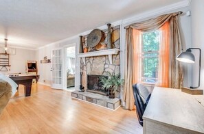 Ein geräumiges Wohnzimmer mit Kamin aus Stein, einer Billardkugel und einer gemütlichen Sitzecke.