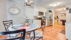 A modern kitchen with white cabinets, a stainless steel refrigerator, and a microwave. There is a dining table with chairs and a clock on the wall. - 3-bedroom house in awesome Ellenwood with cool AC breeze (Ellenwood)