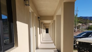 Käytävällä on laatoitettu lattia, valaisimet ja sen ulkopuolella on pysäköity ajoneuvo.