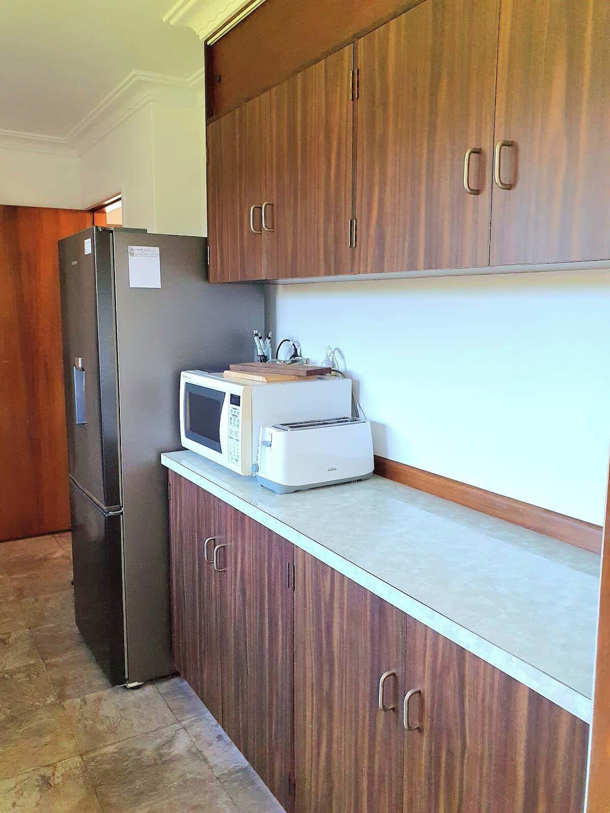 A kitchen with wooden cabinets, a refrigerator, a microwave, and a toaster.
