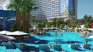 Un hôtel doté d’une grande piscine, de palmiers et d’un bâtiment moderne avec des balcons.