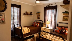 A bedroom with two beds, a nightstand, a lamp, and a hanging plant. - Doc Holliday Western Bungalow Walk to Downtown (Denison)