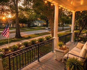 A porch with a railing, outdoor seating, and a flag. - Doc Holliday Western Bungalow Walk to Downtown (Denison)