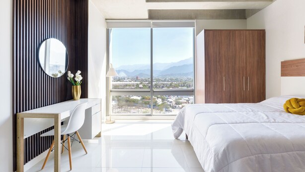 Ein modernes Schlafzimmer mit großem Fenster, Schreibtisch, Bett und Kleiderschrank.