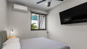 Une chambre avec un lit, un ventilateur de plafond, un climatiseur, une fenêtre donnant sur un beau paysage et un téléviseur fixé au mur.