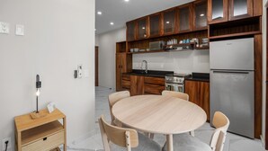 Une cuisine moderne avec des meubles en bois, un réfrigérateur en acier inoxydable et une table de salle à manger ronde, accompagnée de chaises.