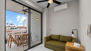 Un salon moderne avec un canapé vert, une table d’appoint en bois et un coin repas comprenant une table et des chaises.