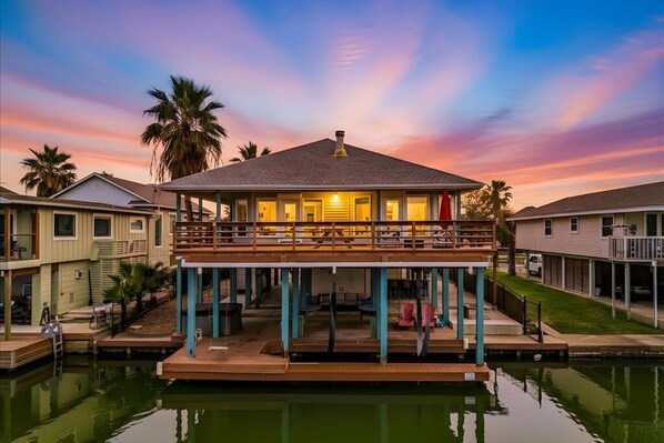 Una propiedad frente al mar con terraza techada, piscina y cielo al atardecer.