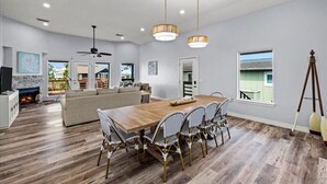 A spacious living room with a wooden dining table, a sofa, and a ceiling fan.
