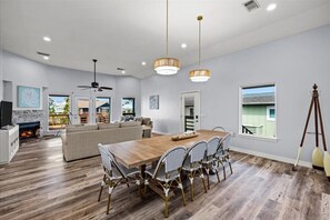 A spacious living room with a wooden dining table, a sofa, and a ceiling fan.