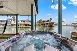 Un jacuzzi con vistas a propiedades frente al agua y una zona cubierta.