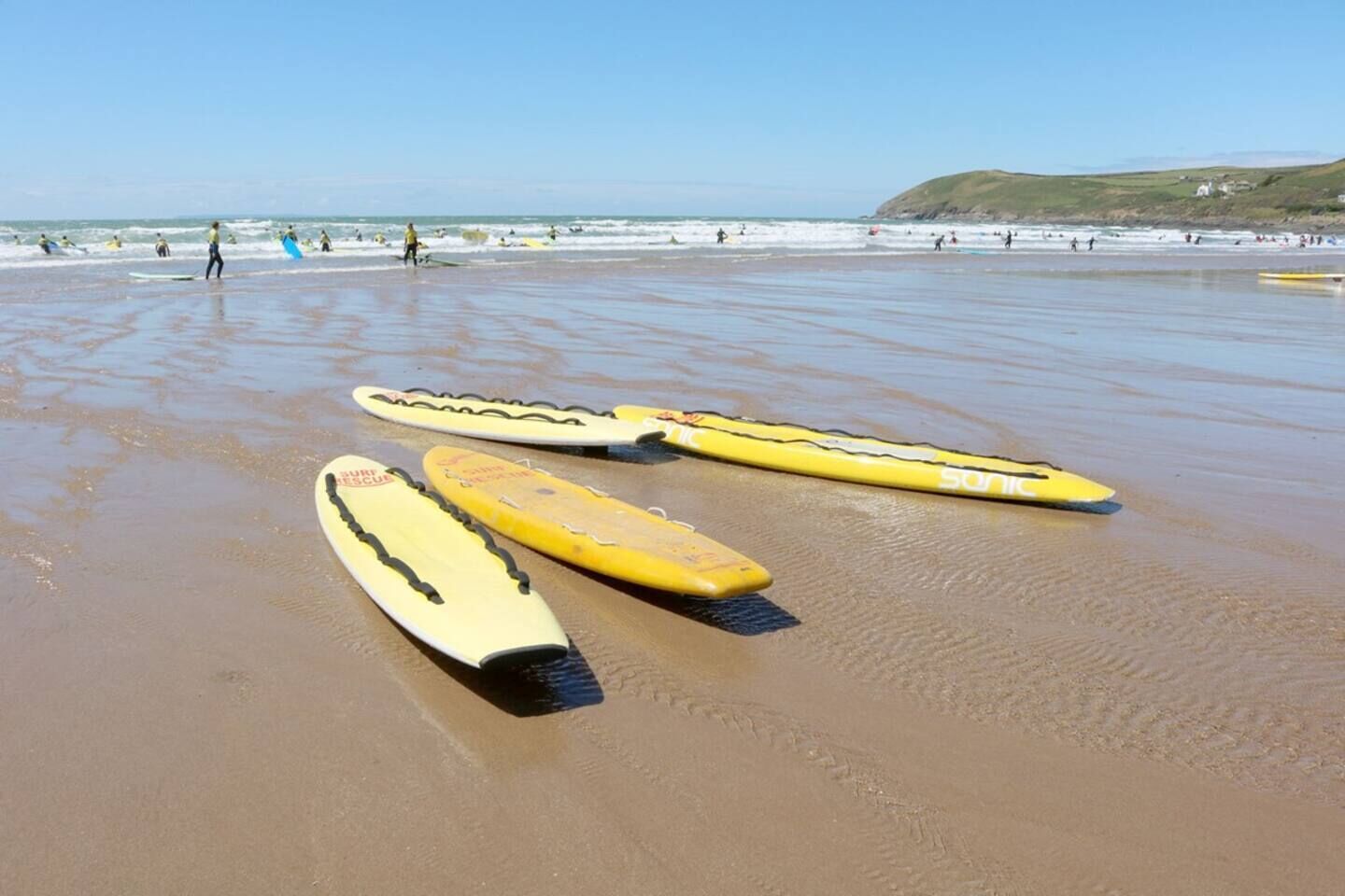A beach with surfboards and people in the water.
