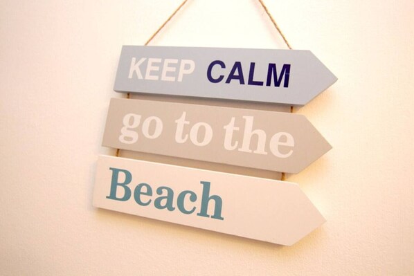 Ein Schild mit der Aufschrift 'KEEP CALM go to the Beach' in Form eines Wegweisers.