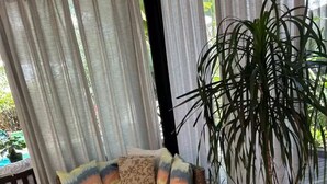 A living room with a wicker sofa, a potted plant, and a woven basket. - Experience Maresias to the fullest: with your feet in the sand, comfort, and exclusivity. (São Sebastião)