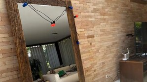 A modern living room with a large mirror, brick walls, and a TV. - Experience Maresias to the fullest: with your feet in the sand, comfort, and exclusivity. (São Sebastião)