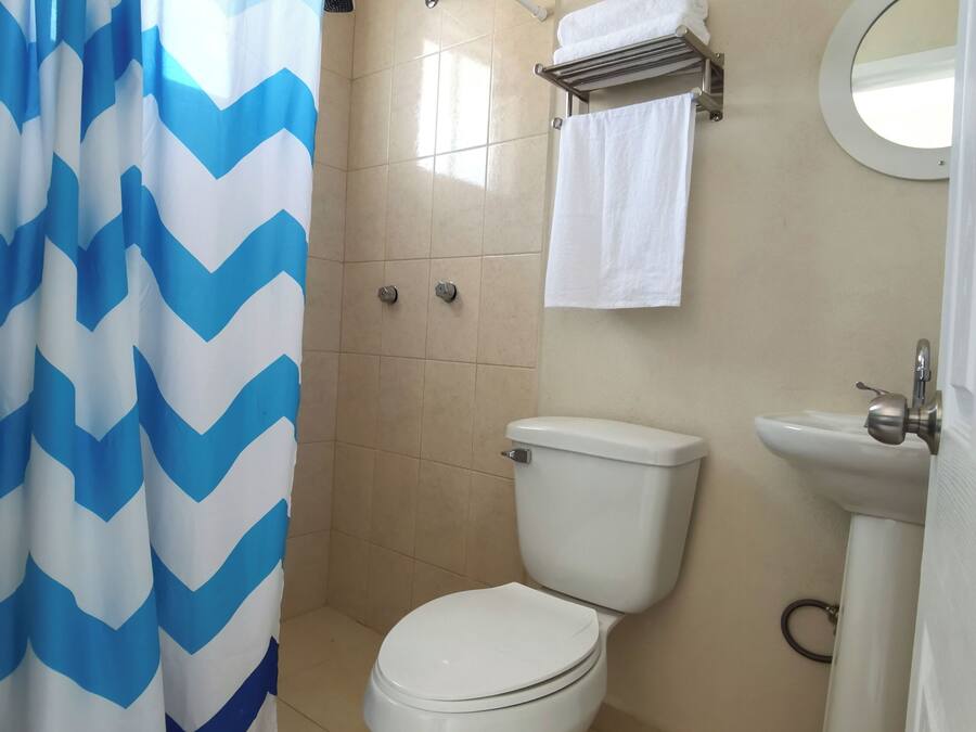 A bathroom with a shower curtain, a toilet, a sink, and a towel rack.