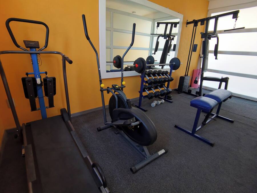 A gym with exercise equipment, a bench, and a mirror.