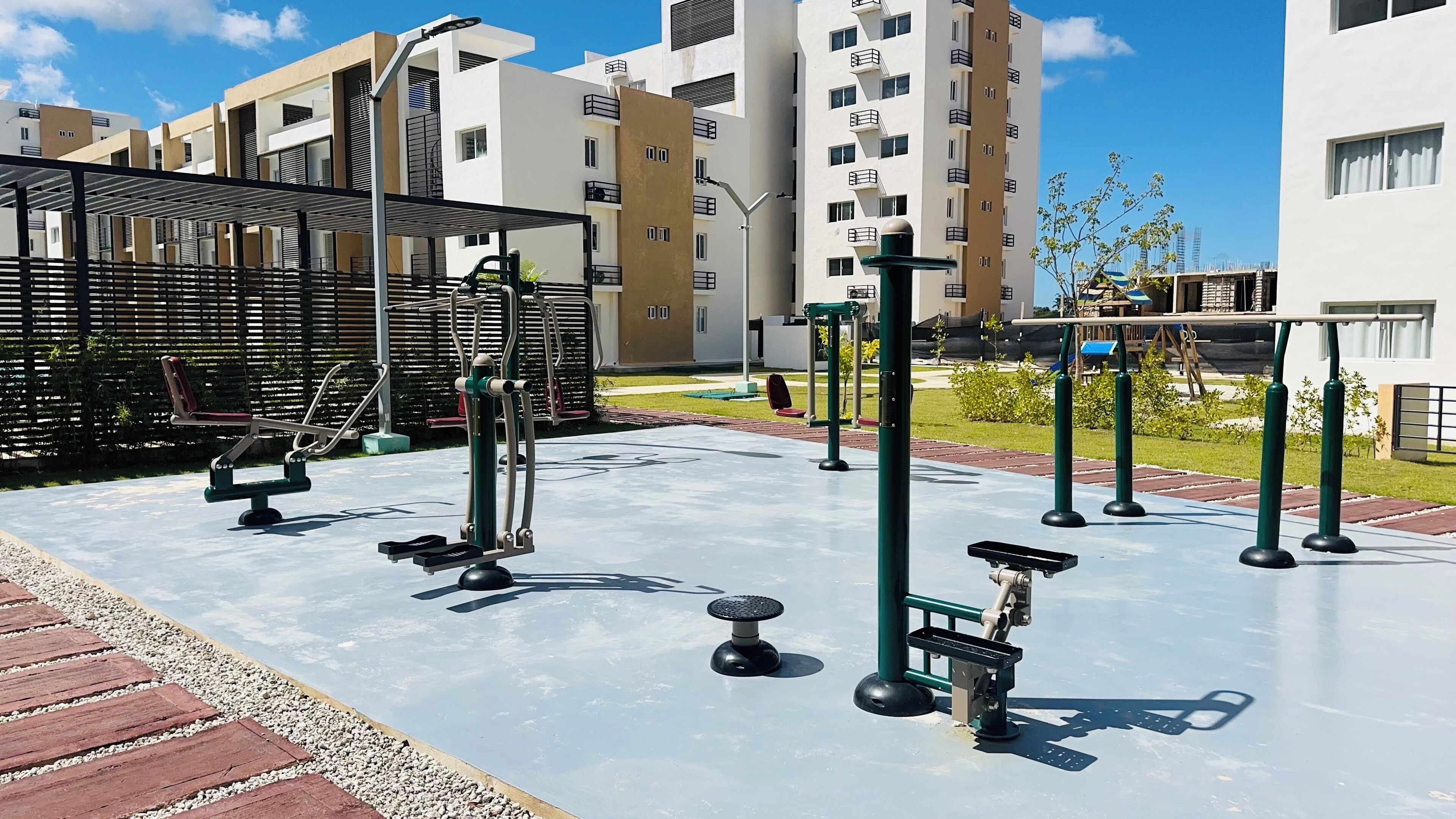 Una palestra all'aperto con attrezzi per esercizi, circondata da una zona pavimentata e un pontile in legno.