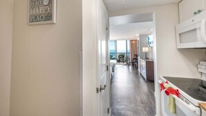 Habitación de hotel con vista a la playa, un área de cocina y un comedor con vistas.
