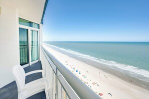 Un balcon donnant sur une plage, une chaise et une rambarde.