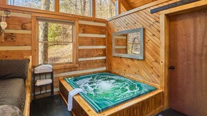 A wooden cabin with a hot tub, a bed, and a door. - Peace, Quiet, and a Cozy Cabin (Sevierville)
