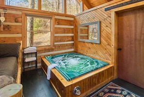 A wooden cabin with a hot tub, a bed, and a door. - Peace, Quiet, and a Cozy Cabin (Sevierville)