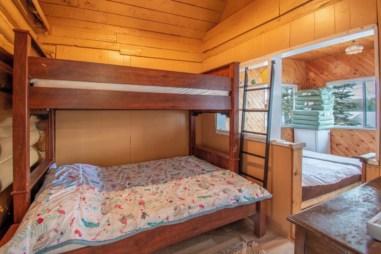 A bunk bed room with wooden walls and a window.