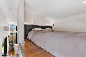 Un dormitorio moderno con cama, chimenea y vistas al exterior.