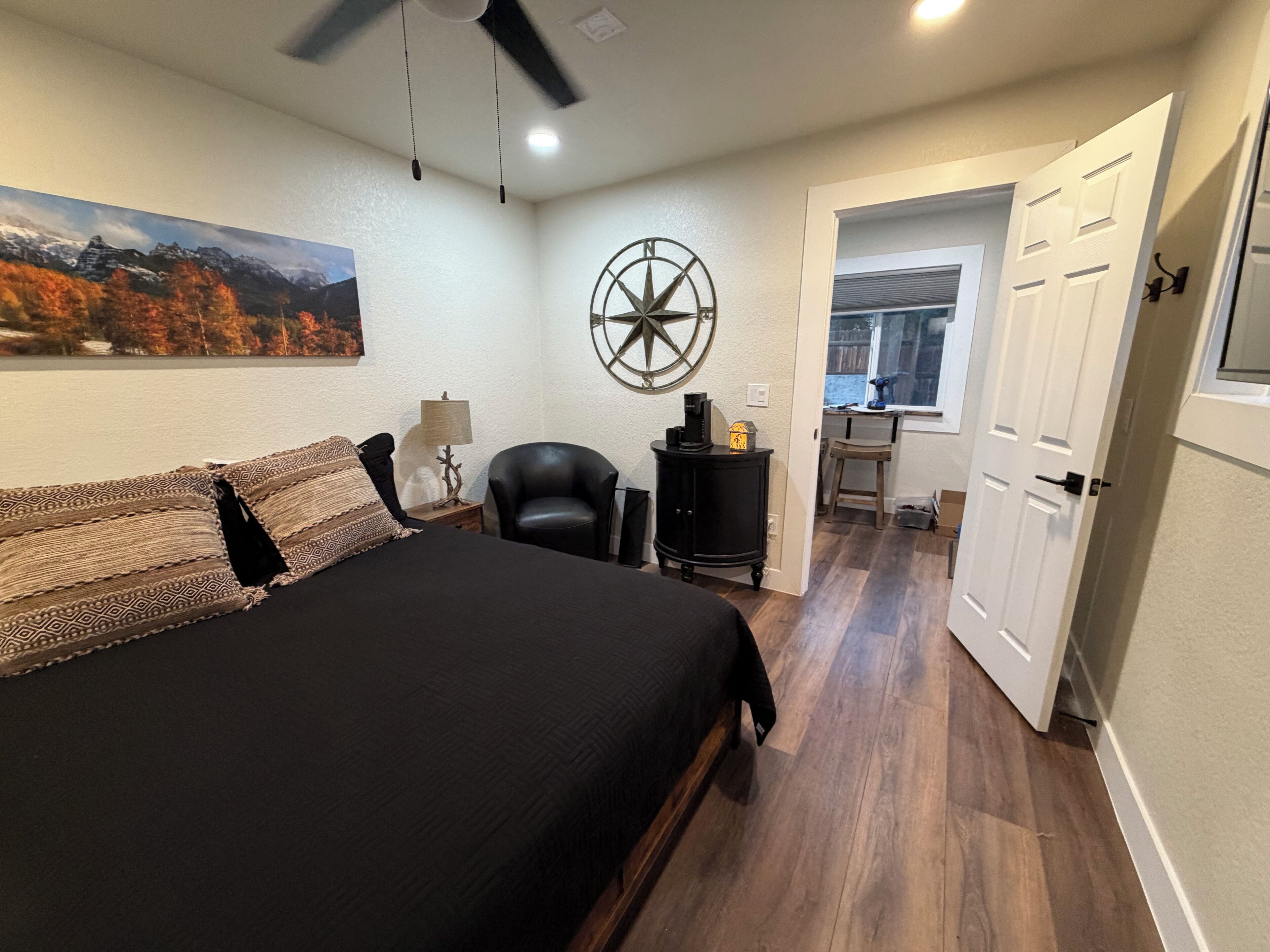 A bedroom with a large bed, a desk, a chair, a lamp, and a wall clock.