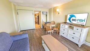 Un salon de taille réduite comprenant un canapé, une table à manger et un téléviseur posé sur une commode.