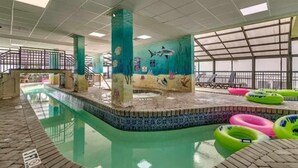 Une piscine intérieure ornée d’une fresque représentant la vie marine, dotée d’un sol carrelé et de chaises longues.