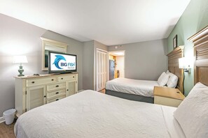 Une chambre d’hôtel avec deux lits, une télévision, une commode et une salle de bain visible à travers une porte ouverte.