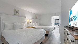 Ett hotellrum med två sängar, en tv och utsikt över korridoren.
