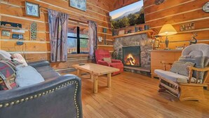 L’intérieur d’un chalet confortable, avec une cheminée, des murs en bois et un coin salon accueillant.