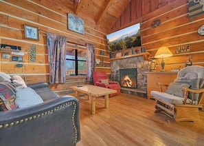Ein gemütliches Blockhaus-Interieur mit Kamin, Holzwänden und einer bequemen Sitzecke.