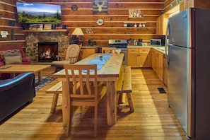 Ein gemütliches Blockhaus-Interieur mit Kamin aus Stein, einem Holzespeisesaal und einer Küchenzeile.