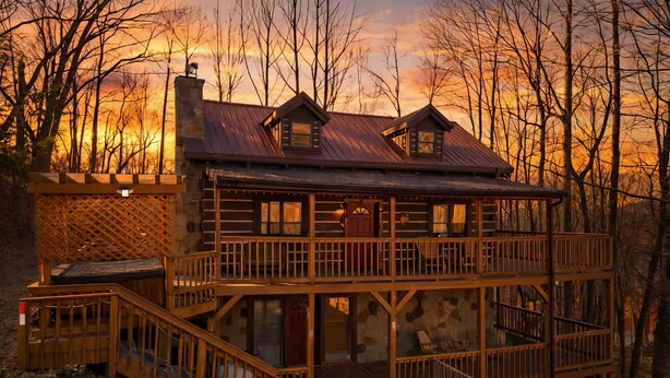 Une cabane en rondins à deux étages, dotée d’un balcon et d’un escalier menant à l’entrée.