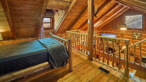 Une chambre mansardée chaleureuse, avec un lit, un escalier en bois et une cheminée.