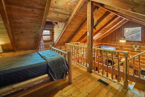 Ein gemütliches Schlafzimmer im Dachgeschoss mit einem Bett, einer Holztreppe und einem Kamin.