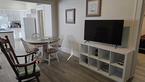 En moderne stue med spiseplads, et fladskærms-tv og indbyggede reoler.