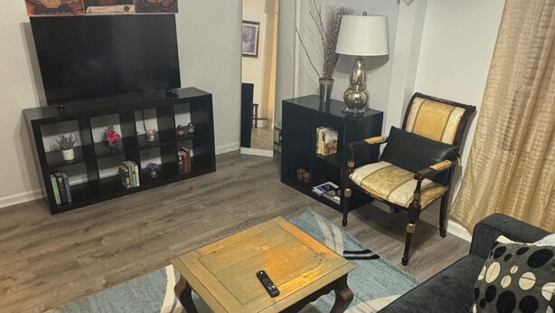 Un salon comprenant un canapé, une table basse, un meuble pour la télévision agrémenté d’objets décoratifs et un fauteuil.