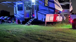 A large RV with a covered living area, a ladder, and a ramp leading to the entrance. - The Slayground of the Dakotas Private MX Retreat (Dickinson)