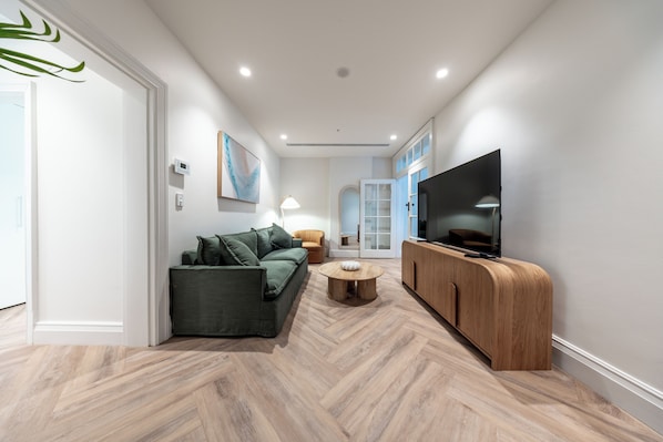 Una sala de estar moderna con un sofá, una mesa de centro, un televisor y un aparador de madera.