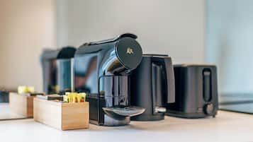 A coffee machine with a black lid and a logo, a coffee maker, and a coffee pot on a countertop.