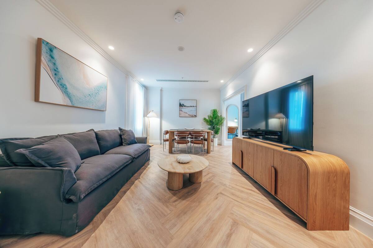 Ein modernes Wohnzimmer mit Sofa, Couchtisch, Fernseher und Holzschrank.