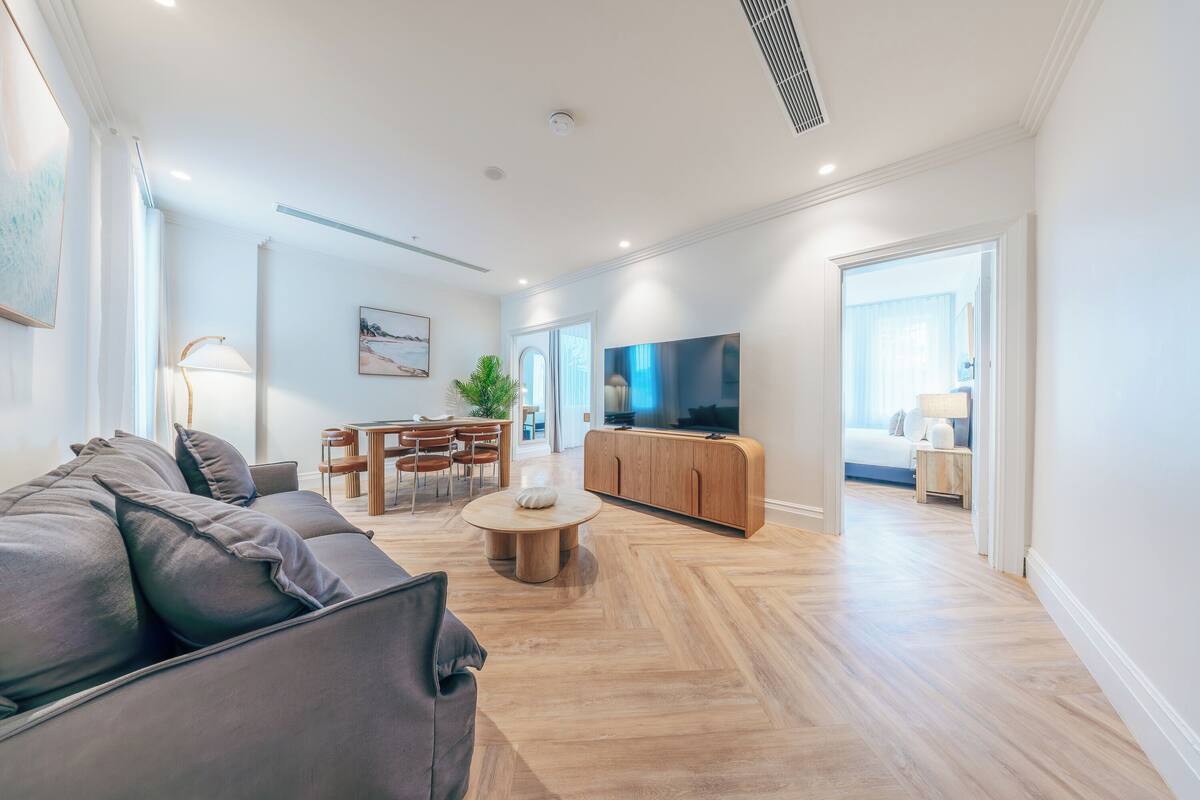 Ein modernes Wohnzimmer mit einer Couch, einem Esstisch, einem Fernseher und Holzböden.