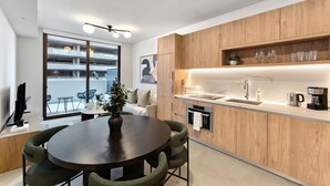 Une cuisine moderne avec des meubles en bois, un plan de travail en marbre et un coin repas comprenant une table ronde et des chaises.