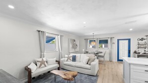 A modern living room with a sofa, coffee table, and dining area. - Greek-style beach oasis. Close drive to the beach and Mercato (Naples)