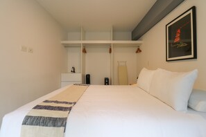 A hotel room with a bed, a wardrobe, a bedside table, and a framed picture on the wall. - w* | Deluxe 1BR Apartment in Heart of San Isidro (San Isidro)