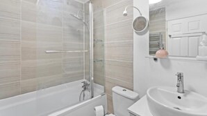 Um banheiro moderno com chuveiro de vidro, pia branca e vaso sanitário.